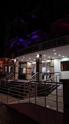 A hotel entrance with a sign reading 'BROTHERS HOTEL' and a staircase leading to the entrance.