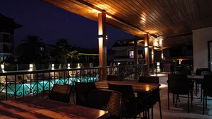 Ein Essbereich im Freien mit Pool, Holz-Pergola und Liegestühlen.