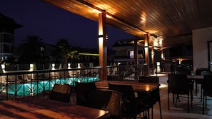 An outdoor dining area with a pool, wooden pergola, and lounge chairs. - 7 Brothers Hotels (Marmaris)