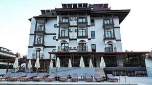 A multi-story hotel with balconies, a pool area with sun loungers, and outdoor umbrellas. - 7 Brothers Hotels (Marmaris)