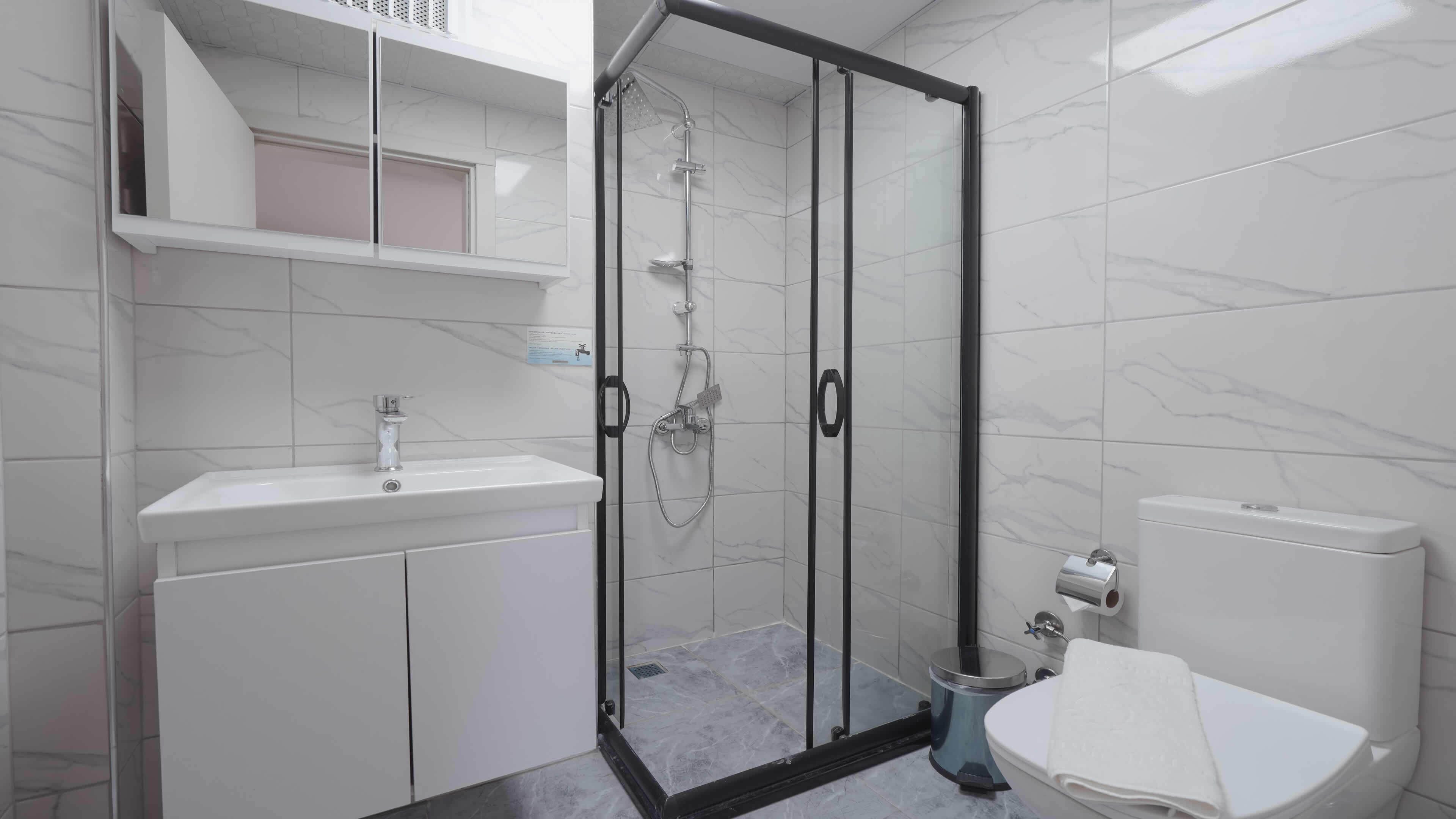 A modern bathroom with a glass-enclosed shower, a white sink, and a toilet.