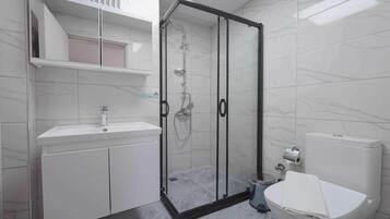 A modern bathroom with a glass-enclosed shower, a white sink, and a toilet.