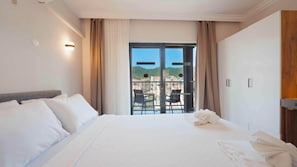 A hotel room with a bed, a balcony with a view of buildings and hills, and a wardrobe. - 7 Brothers Hotels (Marmaris)