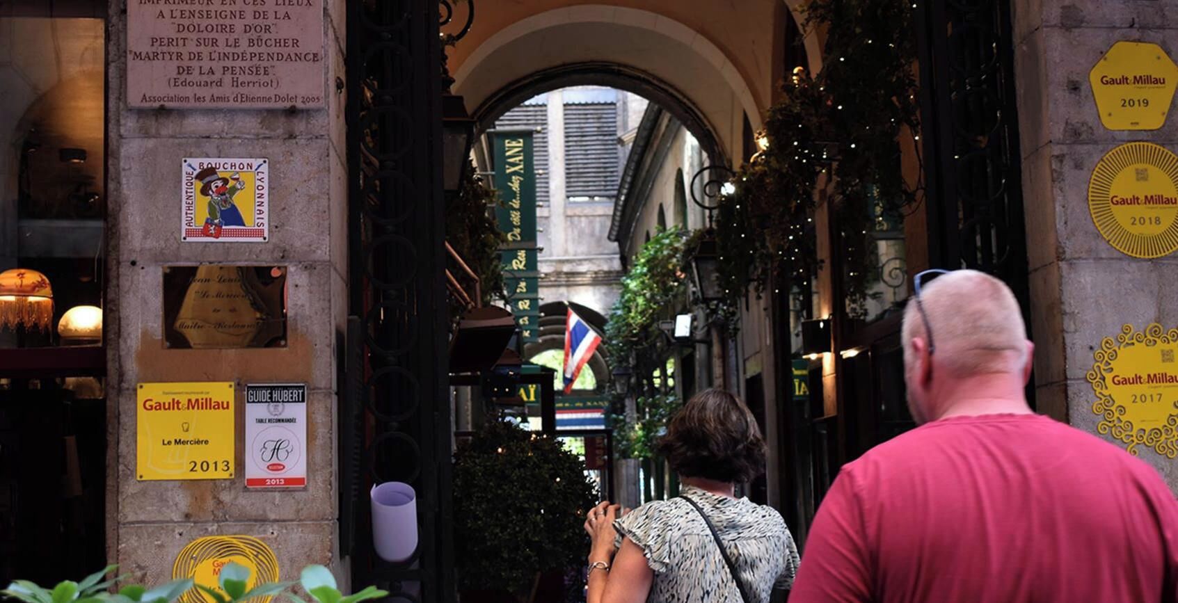 A street view with a building entrance, signs, and a flag.