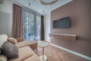 A modern living room with a sofa, a small round table, a mounted TV, and a large window with curtains. - Chmielna Duo Elegant | Warsaw Center & Parking (Warszawa)
