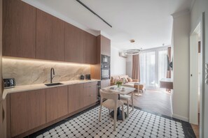 A modern kitchen with wooden cabinets, a marble countertop, and a dining area with a table and chairs. - Chmielna Duo Elegant | Warsaw Center & Parking (Warszawa)