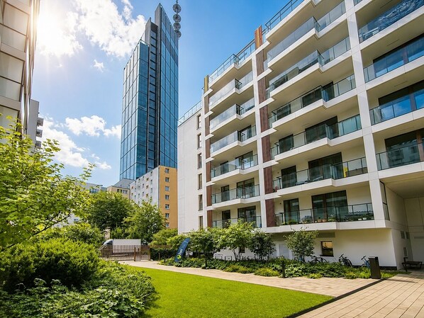 Un edificio moderno con diversi piani, ampie finestre e un giardino curato.