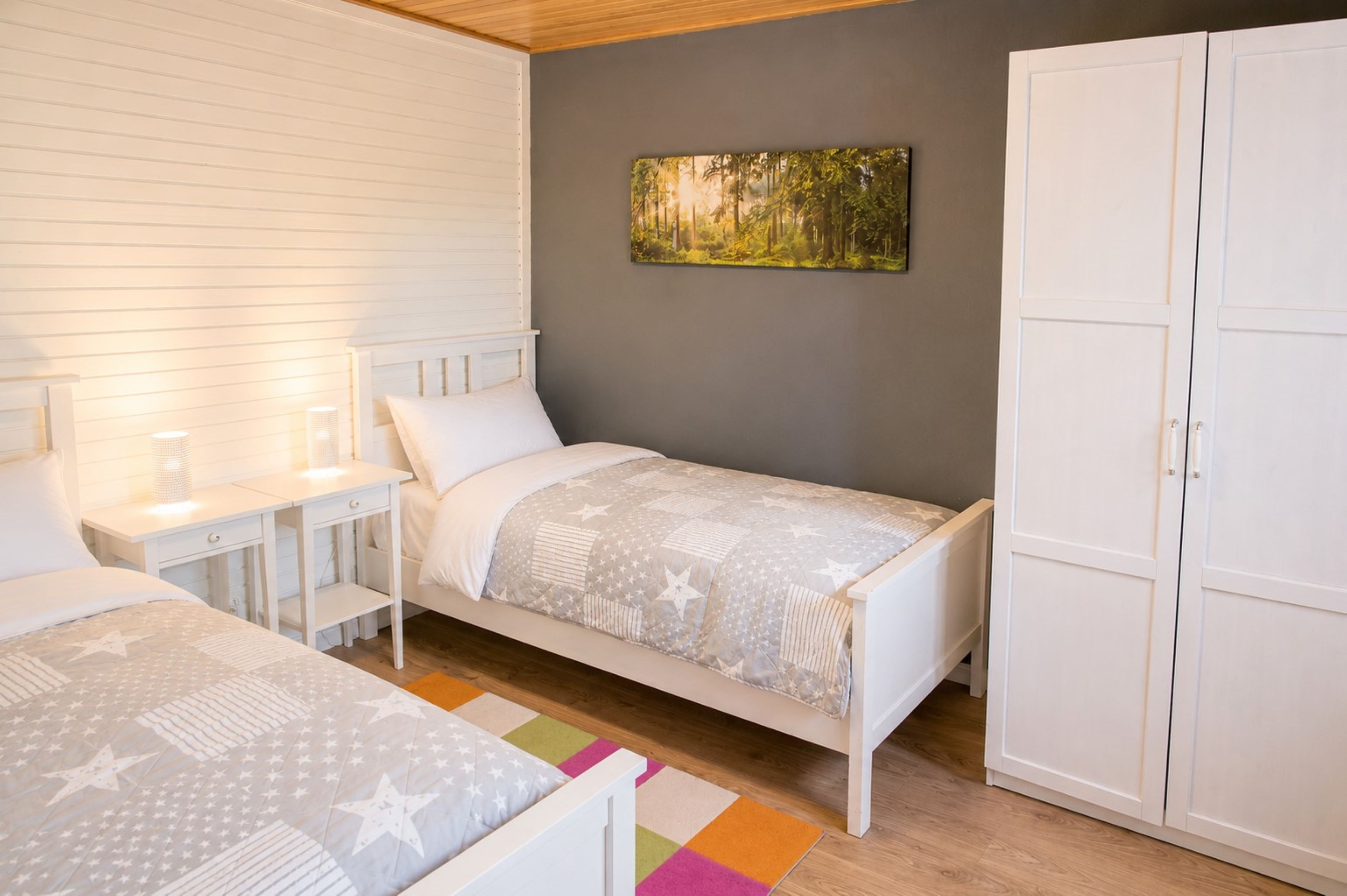 Ein Schlafzimmer mit zwei Einzelbetten, einem Nachttisch, einem Kleiderschrank und einem Bild an der Wand.
