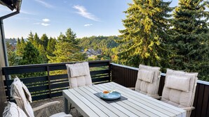 Un patio exterior con una mesa blanca y cuatro sillas, cada una con cojín.