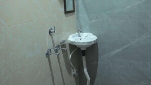 A bathroom with a shower, sink, and a black bucket. - Preksha Palace (Ayodhya)