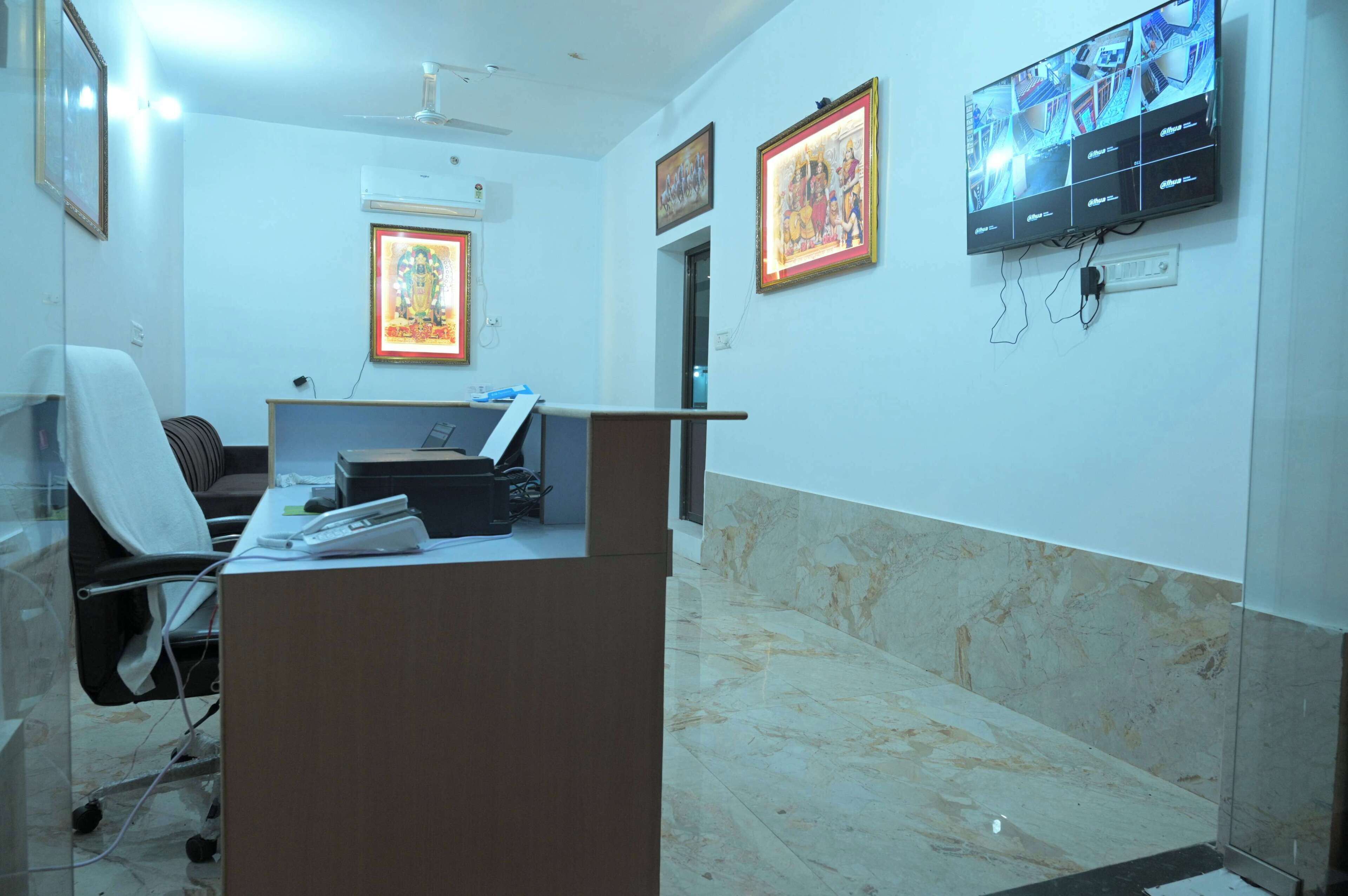 A reception area with a desk, chairs, framed artwork, a television, and a ceiling fan.