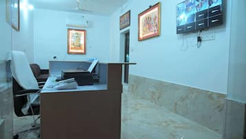 A reception area with a desk, chairs, framed artwork, a television, and a ceiling fan.