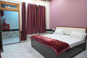 Un dormitorio con cama, ventana con cortinas, extintor y puerta.