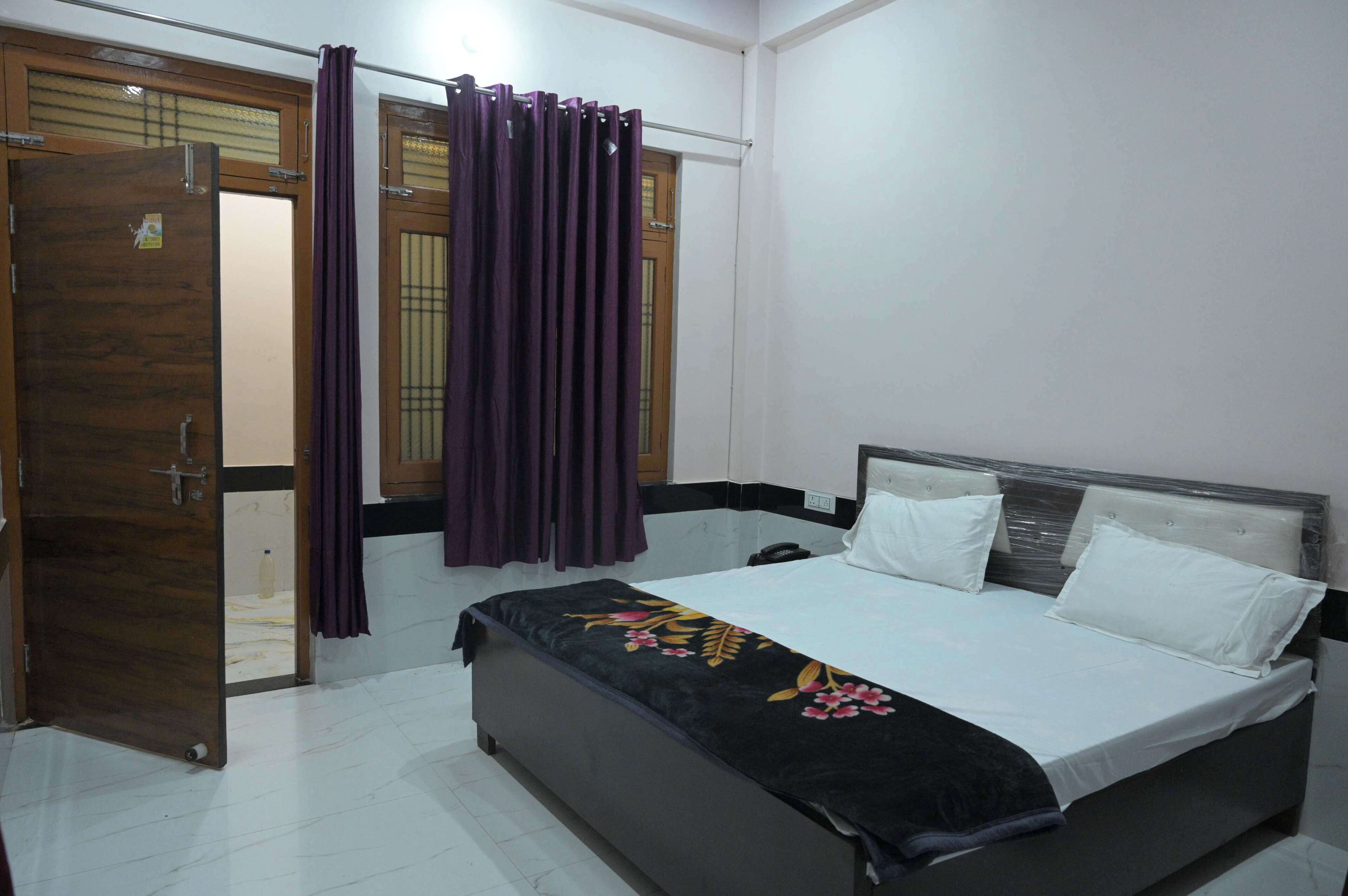 Una habitación de hotel con una cama, una mesita de noche, un teléfono y una ventana con cortinas.