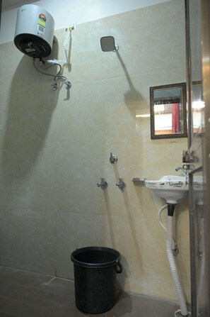 Un baño con ducha, lavamanos, espejo y secador de pelo montado en la pared.