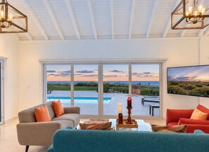 A spacious living room with a large window overlooking a pool and landscape.