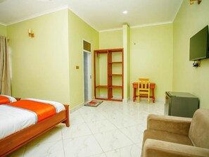 Habitación de hotel con cama, una silla, escritorio, televisor y armario.