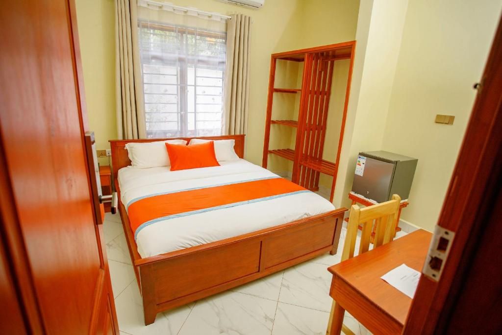 A hotel room with a wooden bed, a TV, a desk, and a wardrobe.