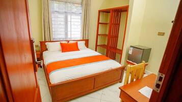 A hotel room with a wooden bed, a TV, a desk, and a wardrobe.