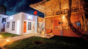 A building with a white exterior, a red door, and a thatched roof structure.