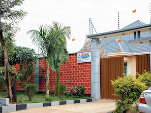 A residential property with a red brick wall, a signboard for 'SALPAT CAMP', and a gated entrance. - Salpat Camp Lodge (Moshi)