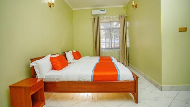 A room with a bed, a nightstand, a window with curtains, and an air conditioning unit.
