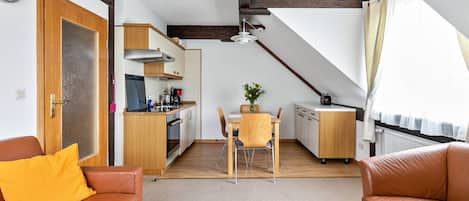 Un espacio habitable compacto con kitchenette, comedor y zona de estar.