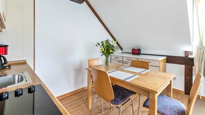 Une cuisine de taille réduite avec une table en bois, des chaises, un évier et un grille-pain rouge.