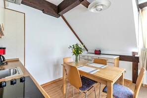 Eine kleine Küche mit Holztisch, Stühlen, einer Spüle und einem roten Toaster.