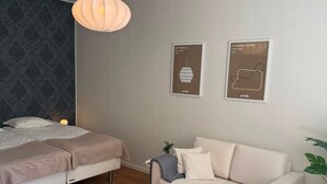 A modern bedroom with a bed, a sofa, a hanging light fixture, and two framed pictures on the wall. - Bright Design District Studio in Helsinki (Helsinki)