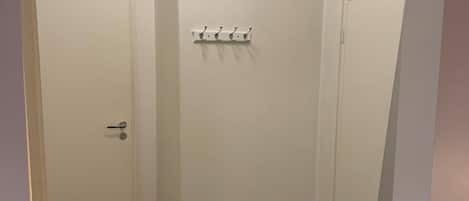 Un cuarto pequeño y cerrado con una puerta, un perchero y un par de zapatos en el suelo.