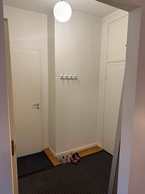 A small, enclosed room with a door, a coat rack, and a pair of shoes on the floor. - Bright Design District Studio in Helsinki (Helsinki)