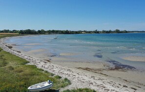 Un bote en una playa arenosa, con aguas tranquilas y cielo despejado.