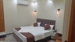 A hotel room with a bed, bedside table, nightstand, and a ceiling fan.