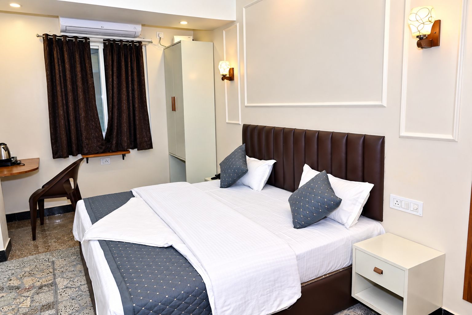 Una habitación de hotel con cama, mesita de noche y escritorio con silla.