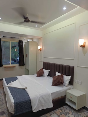 A hotel room with a bed, bedside table, wardrobe, and a ceiling fan.