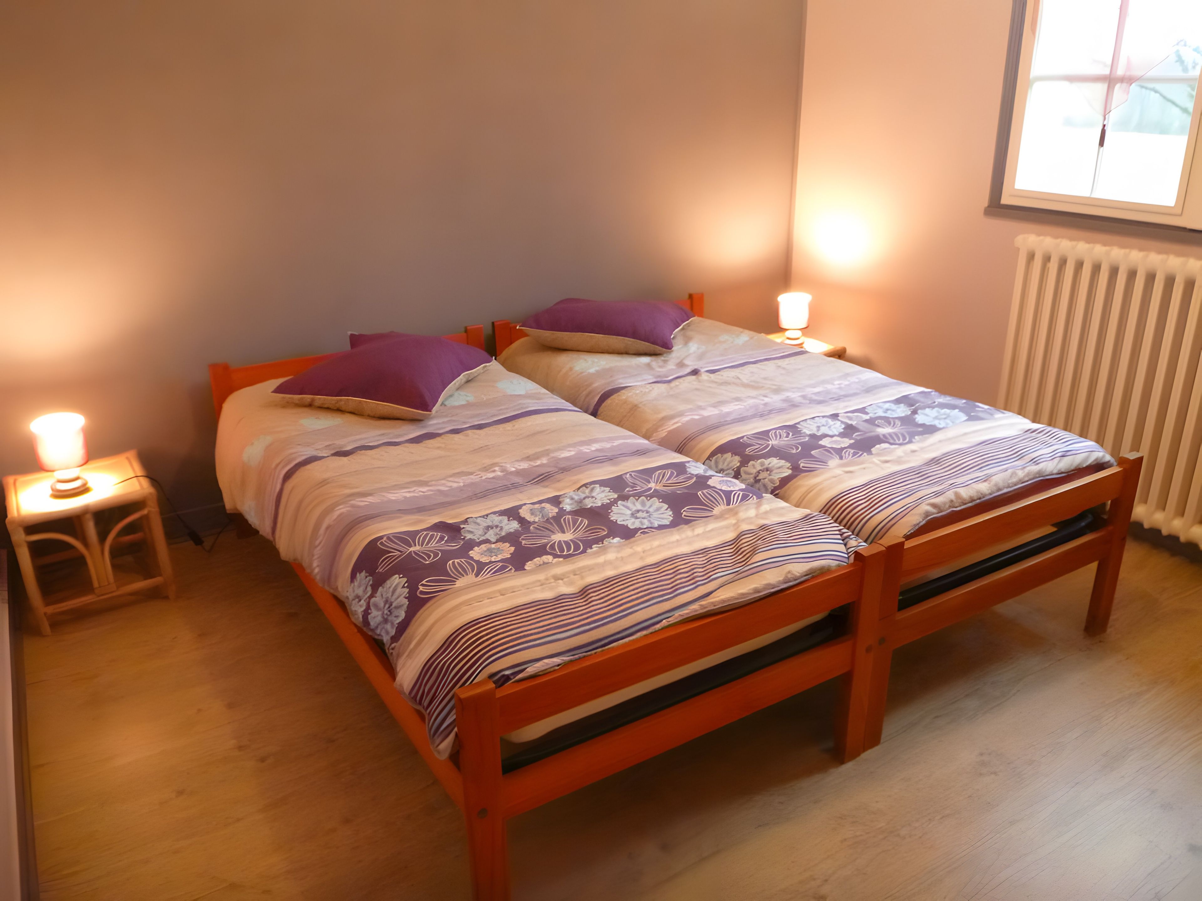 Una cama doble con una colcha de estampado floral y dos lámparas de noche.