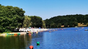 Una zona junto al lago con barcos, una playa de arena y árboles frondosos.