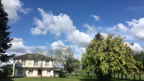 A two-story building with a lawn in front, surrounded by trees and a clear sky. - Large Family Home with Balcony, Garden & Lake Access near Périgord (Sauvagnac)