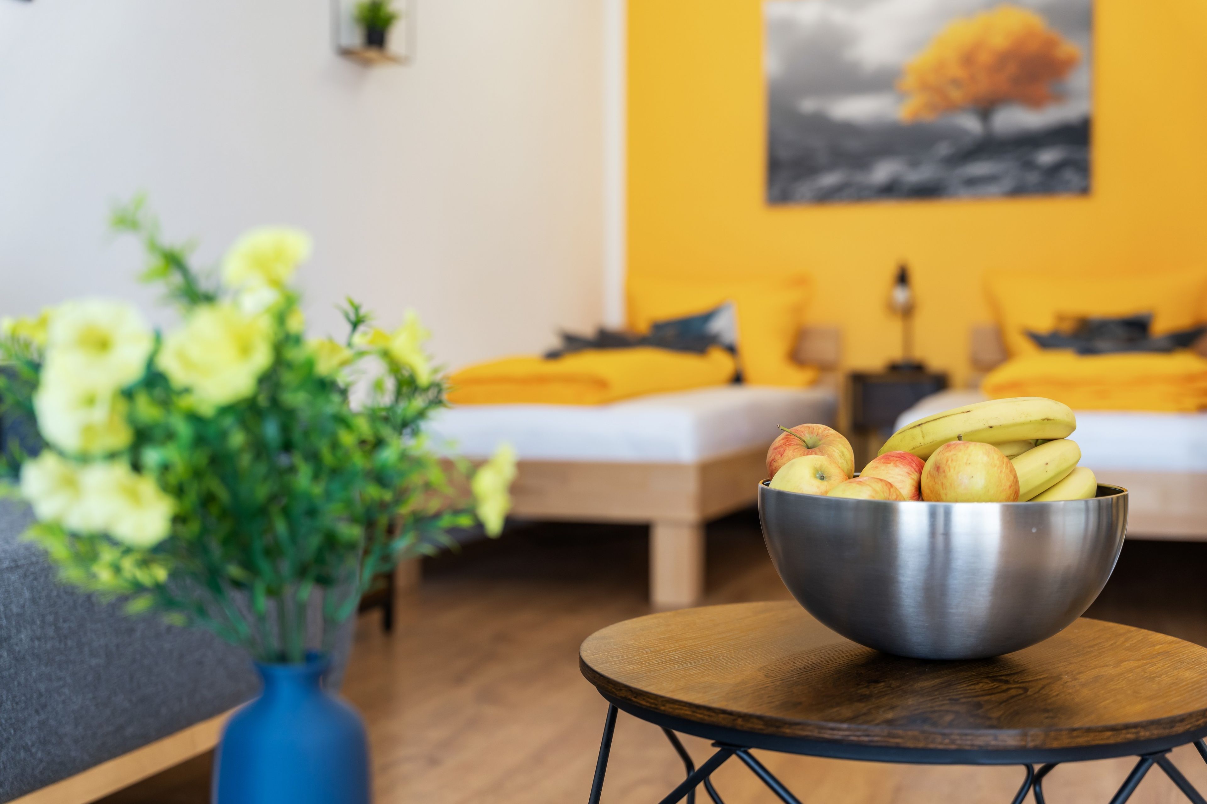 Ein Zimmer mit einem Bett, einer Obstschale und einem Blumenstrauß.