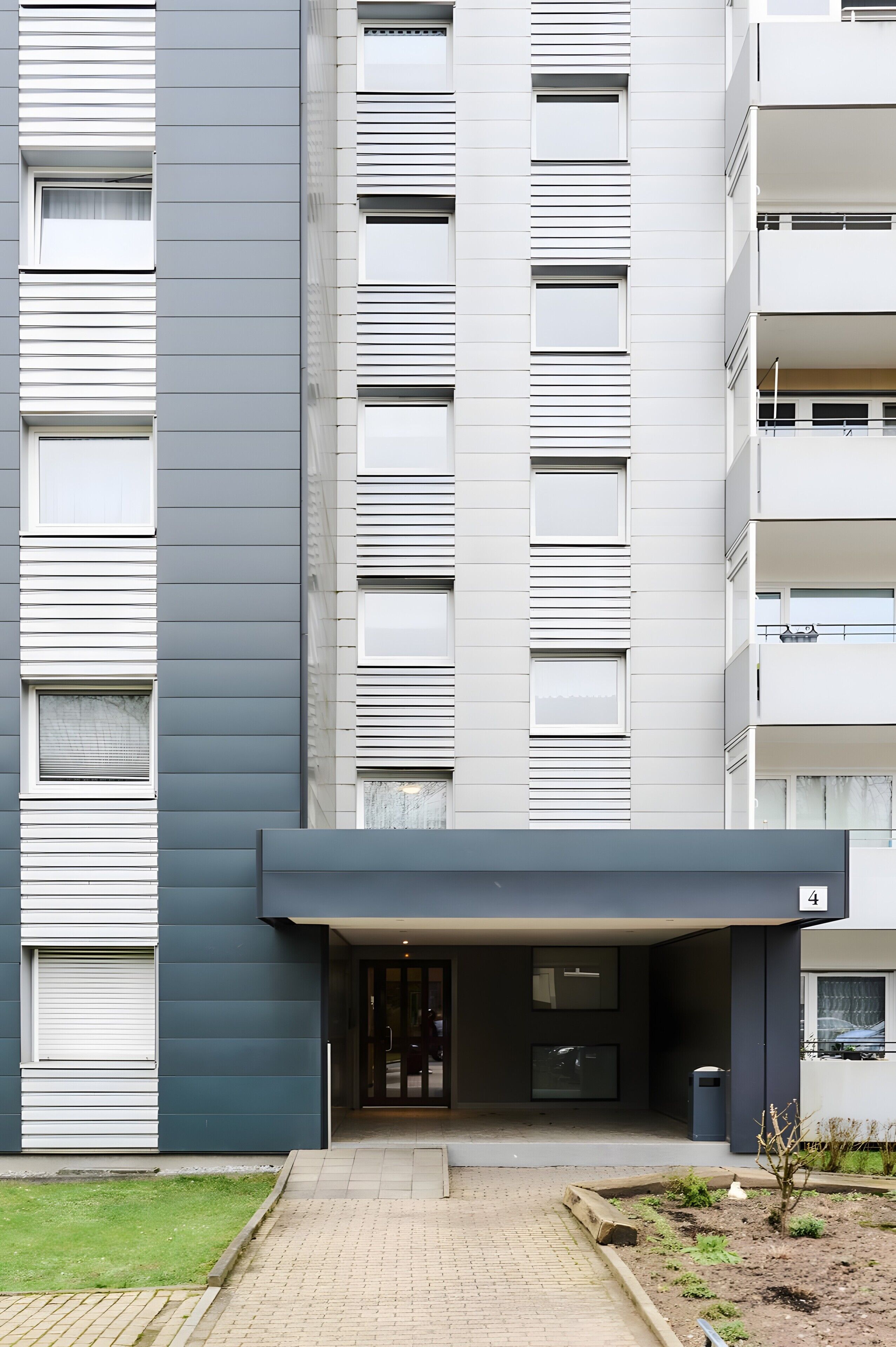 Ein modernes, mehrstöckiges Gebäude mit flacher Fassade, großen Fenstern und einem befestigten Eingangsbereich.