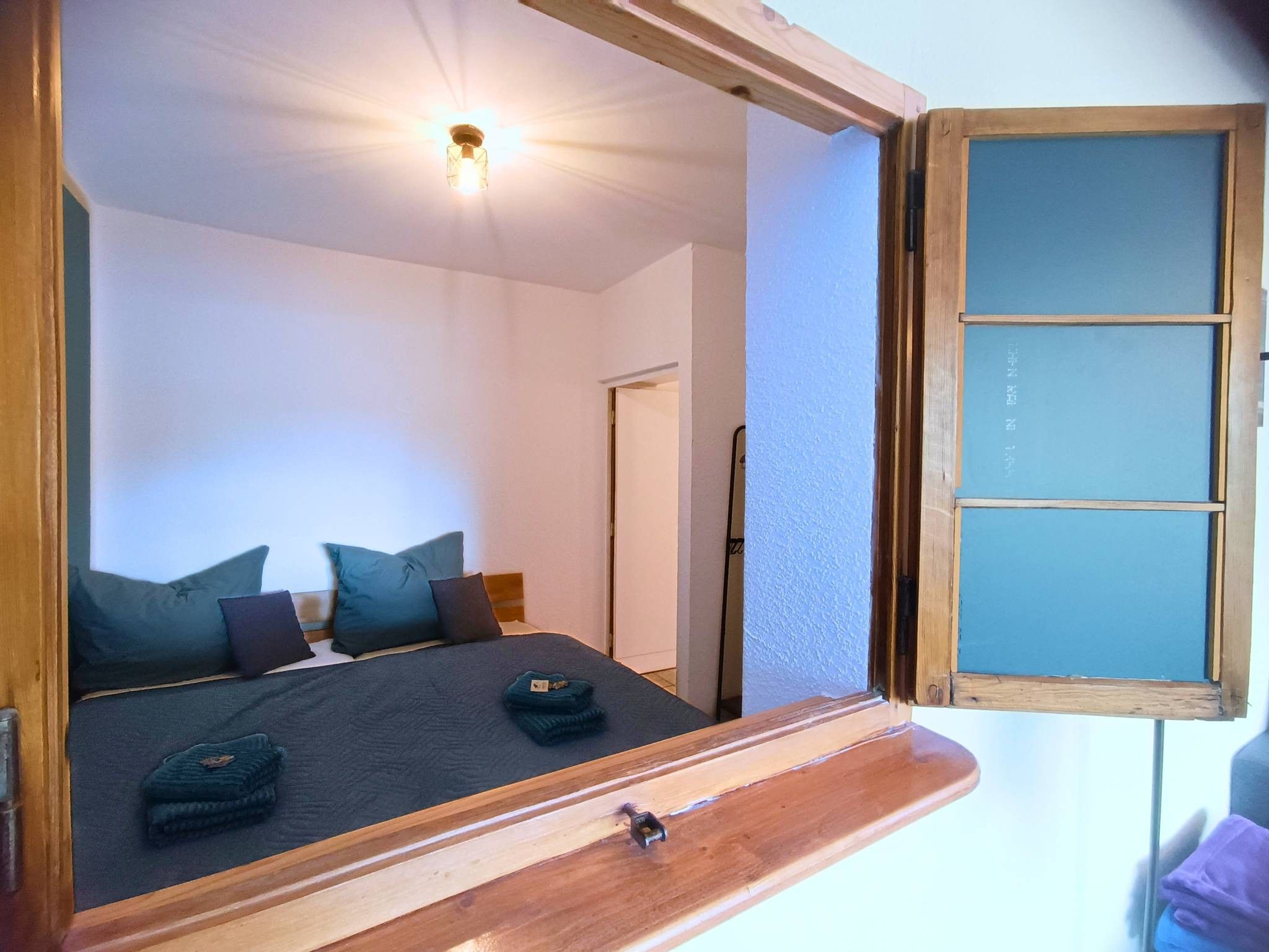 Une chambre à coucher avec un lit, des oreillers, une table de chevet et un miroir.
