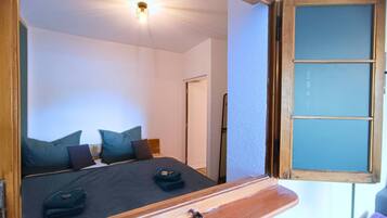 Un dormitorio con cama, almohadas, una mesita de noche y un espejo.