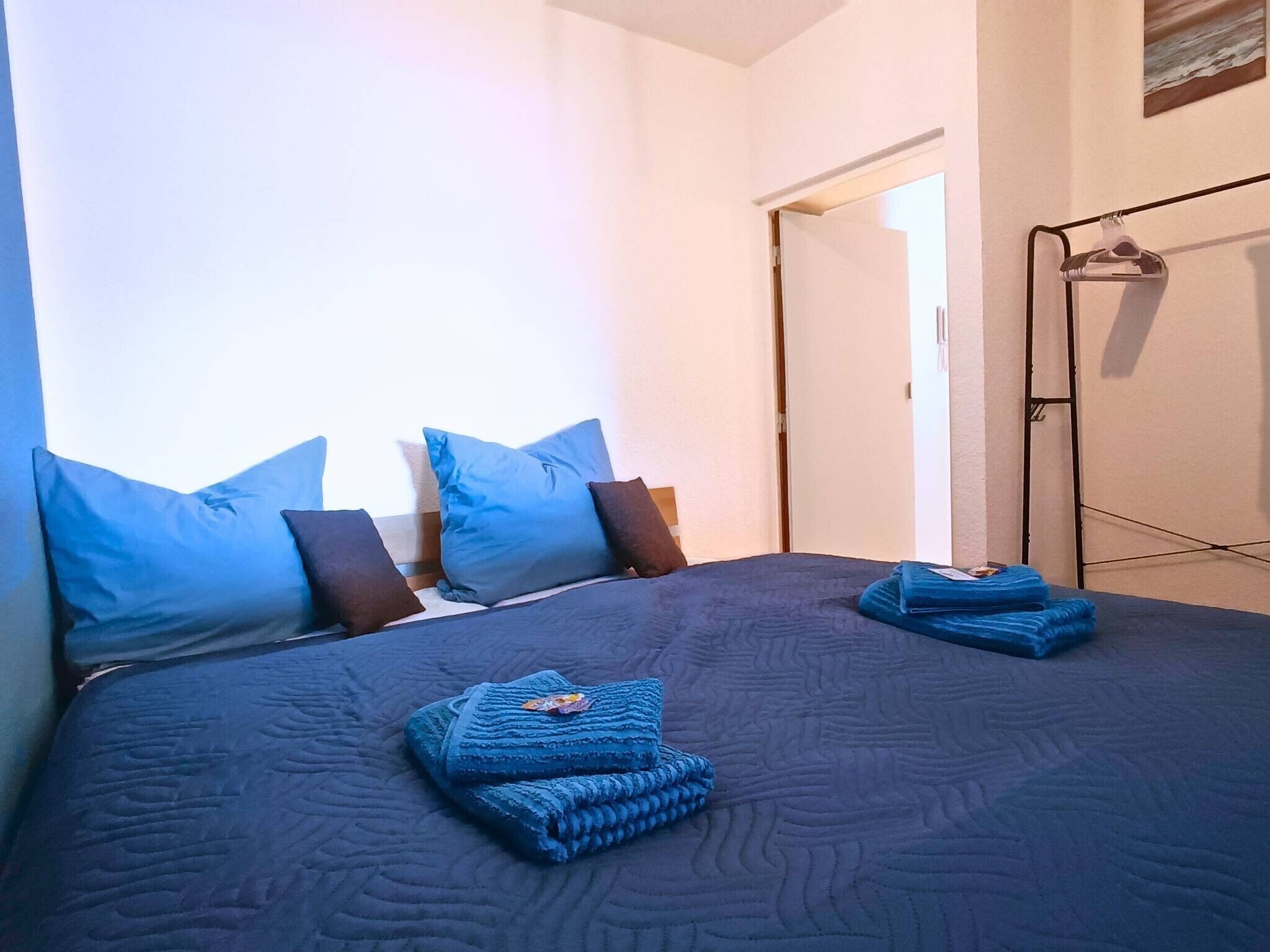 Ein Schlafzimmer mit einem Bett, Kissen und einer zusammengeklappten Decke.