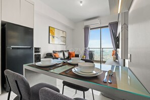 A modern kitchen with a dining area, a black refrigerator, and a dining table set for four. - Eron by Kozystay - Alam Sutera (Tangerang)