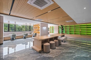 A modern hotel lobby with a wooden ceiling, a large reception desk, seating areas, and a green accent wall. - Eron by Kozystay - Alam Sutera (Tangerang)