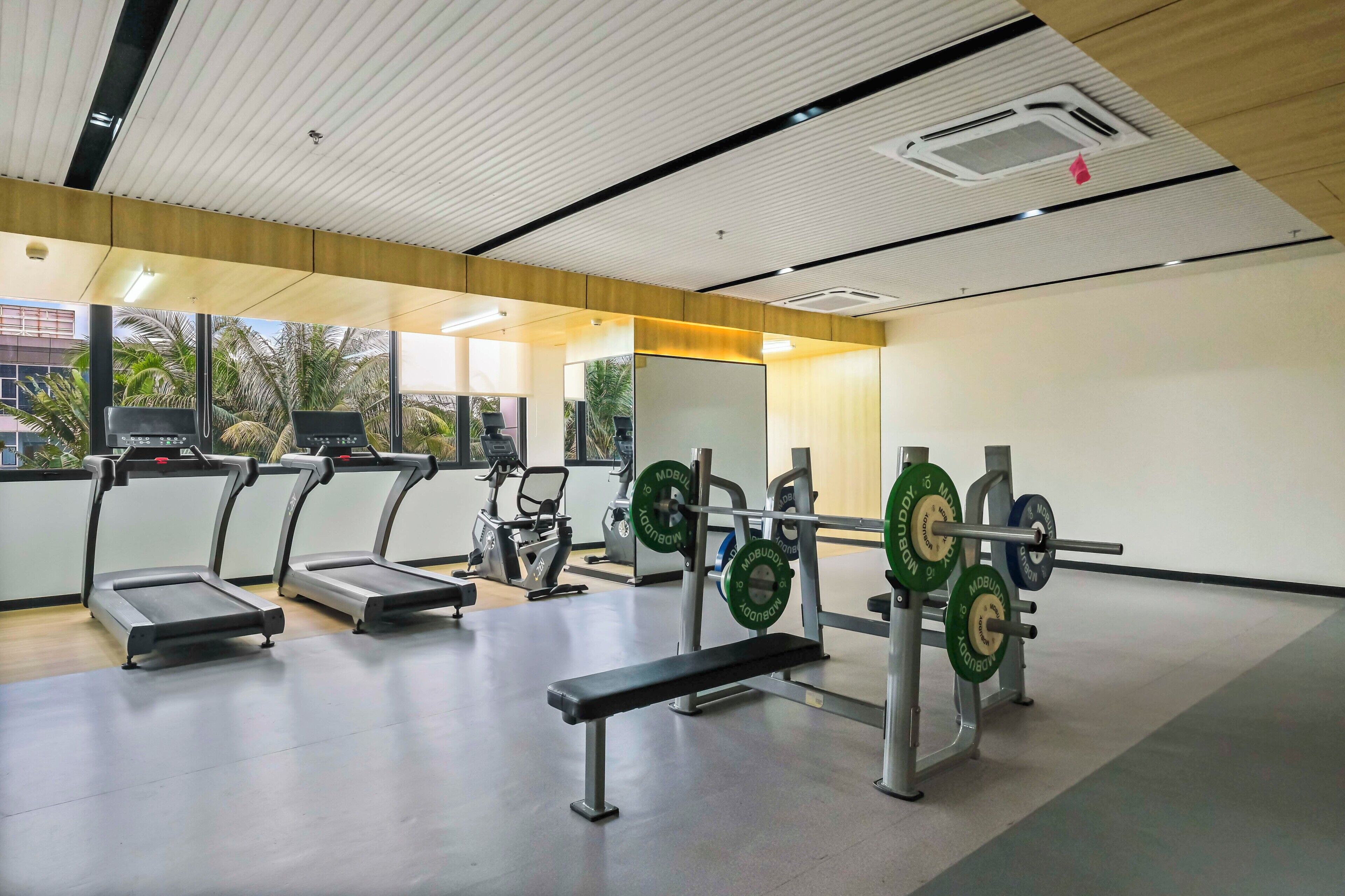 A gym with treadmills, a bench, and weightlifting equipment.