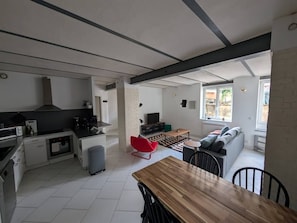 A modern kitchen with a built-in oven and a dining area with a wooden table and chairs. - La Fabrique - Downtown Loft (Nancy)