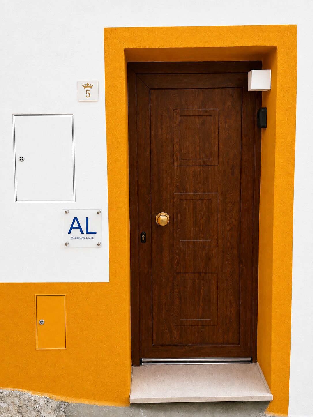 Una puerta de madera con manija de latón, un buzón blanco y un letrero con 'AL' y 'Alojamento Local', indicando un alojamiento local.