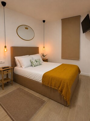 A bedroom with a bed, bedside tables, a wall-mounted TV, and a decorative crown on the wall.